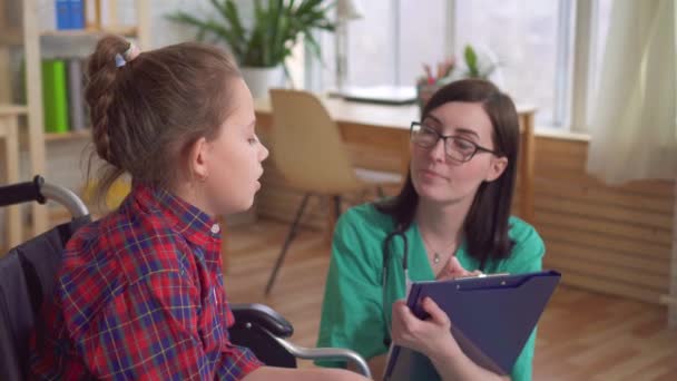 Medico donna che parla con un bambino disabile su una sedia a rotelle — Video Stock