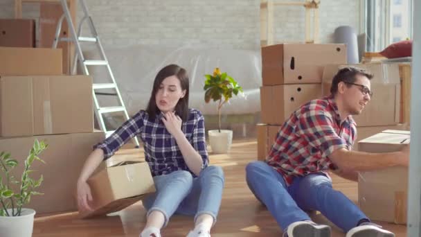 Jovem casal cansado com laptop no fundo de caixas para se mover — Vídeo de Stock