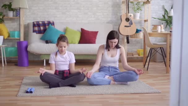 Mutter und Tochter machen Yoga sitzend auf dem Fußboden — Stockvideo