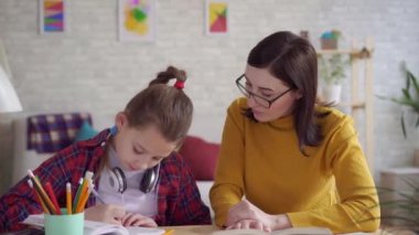 Yakın çekim anne kız ödev yapmak için yardımcı olur