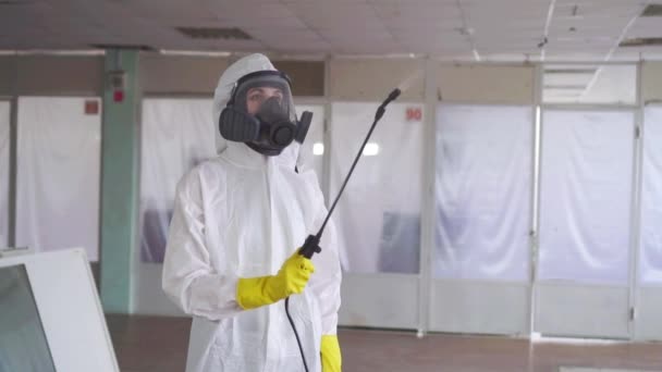 穿着特殊衣服和带喷雾器的防护面罩的消毒器 — 图库视频影像