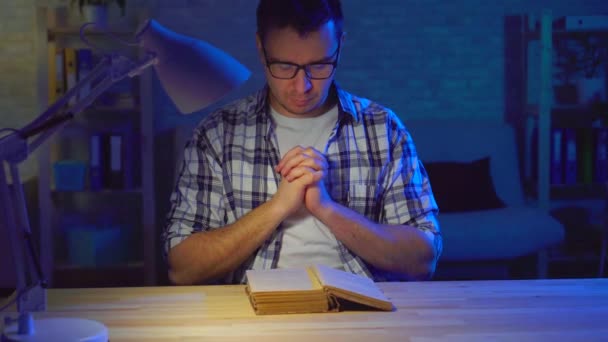 Retrato hombre se sienta en una mesa y lee una oración — Vídeo de stock