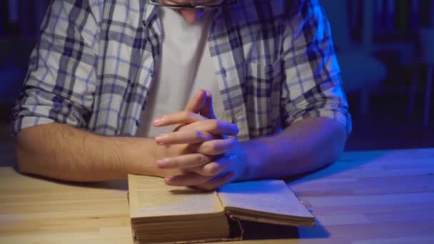 Close up man sits at a table and reads a prayer — Stock Video