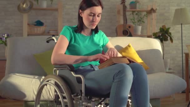 坐在轮椅上的年轻残疾妇女拿着一本书, 读着祈祷词 — 图库视频影像