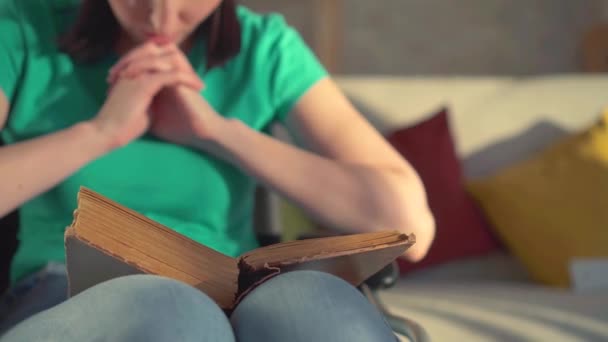 Nahaufnahme einer jungen behinderten Frau, die ein Buch in der Hand hält und im Rollstuhl sitzend ein Gebet liest — Stockvideo