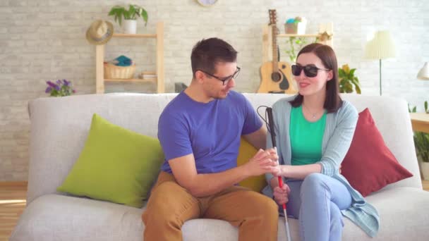 Young man flirts with a blind disabled woman sitting on a sofa — Stock Video