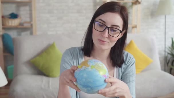 Jonge vrouw onderzoekt een Globe Holding — Stockvideo