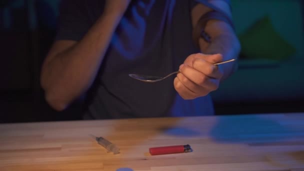Zbliżenie człowieka uzależniony od narkotyków w ciemnym pomieszczeniu przy stole robi zastrzyk — Wideo stockowe