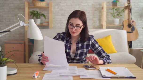 Молодая женщина делает бухгалтерский учет и расчет с калькулятором на рабочем столе — стоковое видео
