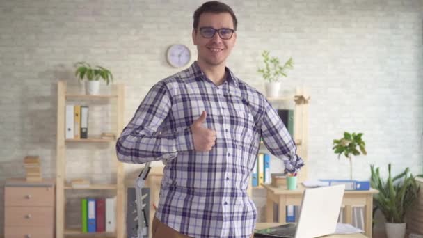 Maschio positivo disabile con una mano amputata guardando in macchina fotografica e sorridente mostrando pollice in su — Video Stock