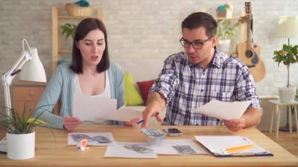 Casal jovem discute ao fazer cálculos de documentos em casa com uma calculadora — Vídeo de Stock