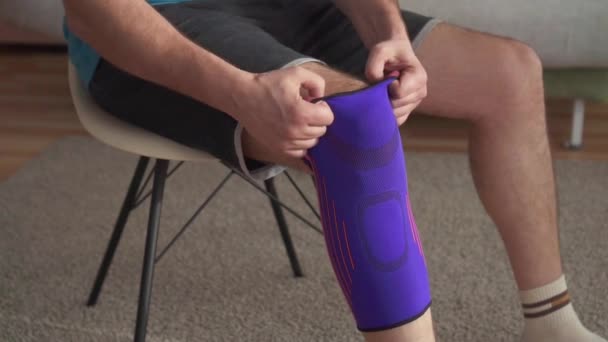 Nahaufnahme eines Mannes, der sich auf das Training vorbereitet, mit einem Verband am Knie. — Stockvideo