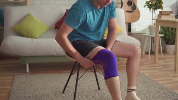 Мужчина спортсмен готовится к тренировкам, с повязкой на колене — стоковое видео