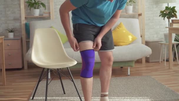 Närbild av en man idrottare efter en skada drar ett bandage på hans knä — Stockvideo