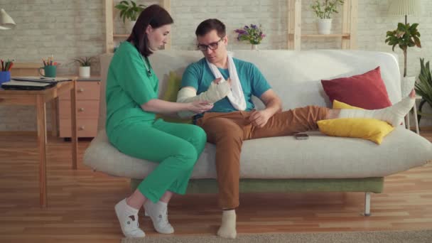 Женщина-врач осматривает мужчину со сломанной рукой — стоковое видео