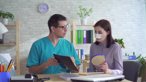 Cirujano plástico médico habla con una mujer joven después de una cirugía plástica en la cara — Vídeos de Stock