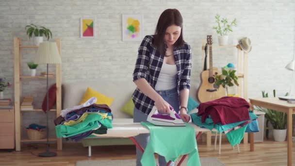 Schattige jonge vrouw in geruite shirt strijken Wasserij ijzer — Stockvideo