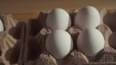 Kadın elinin yakın çekim masanın üzerinde bir karton kutu içinde yumurta koyar.