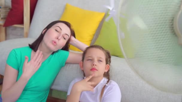 Портрет мать и дочь рядом с вентилятором страдает от жаркой погоды — стоковое видео