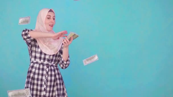 Joven musulmana sonriendo y tirando dinero mirando a la cámara — Vídeo de stock