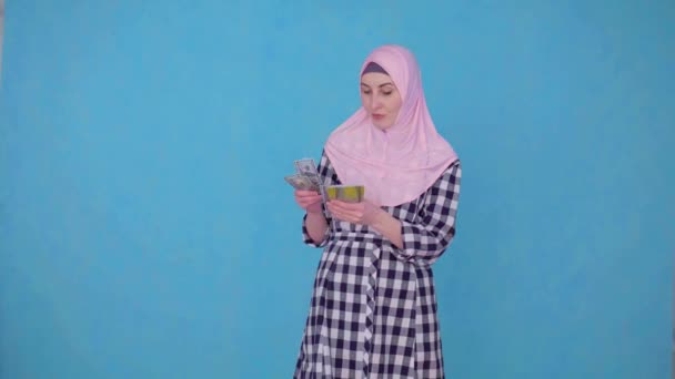 En ung muslimsk kvinna anser en bunt av pengar nöjda, tittar på kameran — Stockvideo