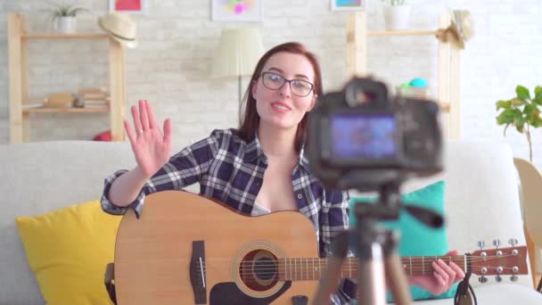 Portrait young woman blogger sitting on the couch with a guitar in his hands in front of the camera slow mo — Stock Video