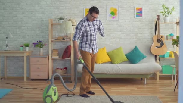 Joven discapacitado sin una mano está limpiando la casa con una aspiradora — Vídeos de Stock