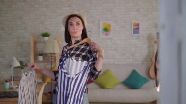Yüzünde yanık izi olan genç bir kadın aynanın önünde kıyafet deniyor.