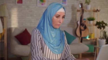 Yüzünde bir yanık bir yara izi ile bir türban portre genç Müslüman kadın bir dizüstü bilgisayarda çalışıyor