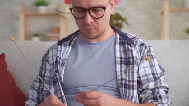Молодой человек с вязальными иголками в руках — стоковое видео