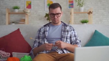 Elinde kollu genç adam yakın bir dizüstü bilgisayarda bir eğitim video örgü öğrenir