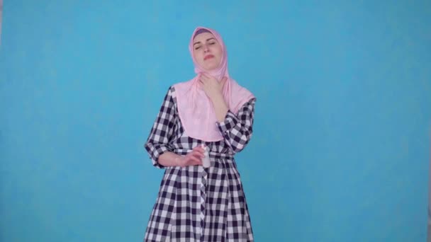 Νεαρή μουσουλμάνα γυναίκα με μαντίλα που έχει πρόβλημα με τον πονόλαιμο, χρησιμοποιεί σπρέι για τη θεραπεία του λαιμού — Αρχείο Βίντεο