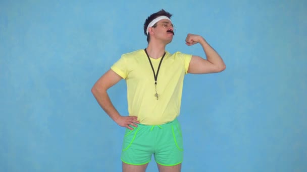 Divertido joven entrenador masculino con un bigote de los años 80 muestra sus músculos y los besa — Vídeos de Stock