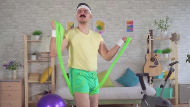 Lustiger Mann macht Fitness zu Hause mit Hilfe von Gummibändern — Stockvideo