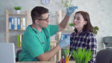 doktor yüzünde büyük benler ile genç bir kadın inceler ve öneriler verir