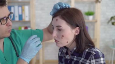 doktor yüzünde büyük benler ile genç bir kadın inceler ve yakın öneriler verir
