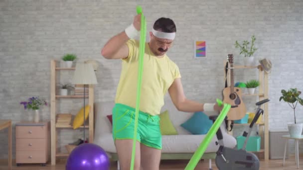 Grappige man verliezer oefening fitness thuis met behulp van elastiekjes — Stockvideo