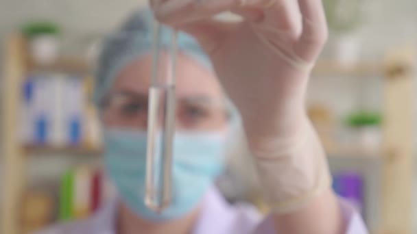 Young woman dropping red liquid into a test tube with a long glass pipette in a chemical laboratory — 비디오