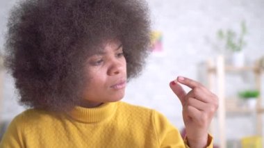 Bir afro saç modeli ile güzel afro-Amerikan kadın bir bardak su bir hap ve içecekler alır