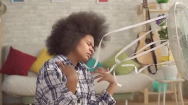 Bir afro saç modeli ile Afrikalı kadın kapatın çalışan bir fan yavaş mo önünde ısı kaçar