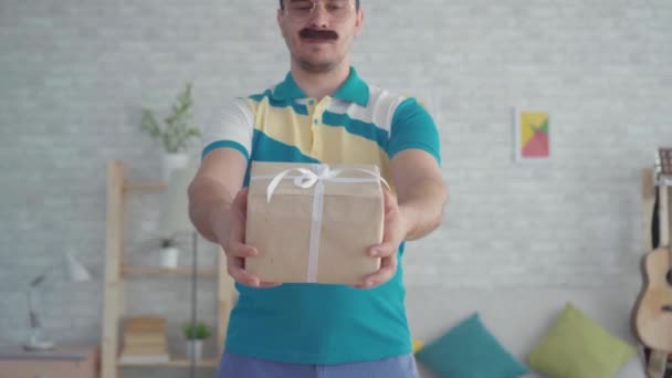 Genç bıyıklı teslimatçı erkek kurye elinde hediye kutusuyla — Stok video