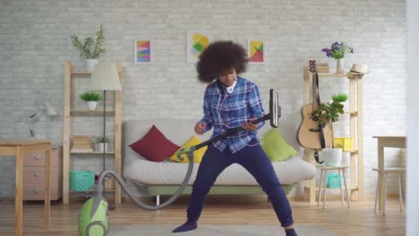 Expresiva positiva afroamericana joven ama de casa aspirar y tocar la guitarra imaginaria — Vídeos de Stock