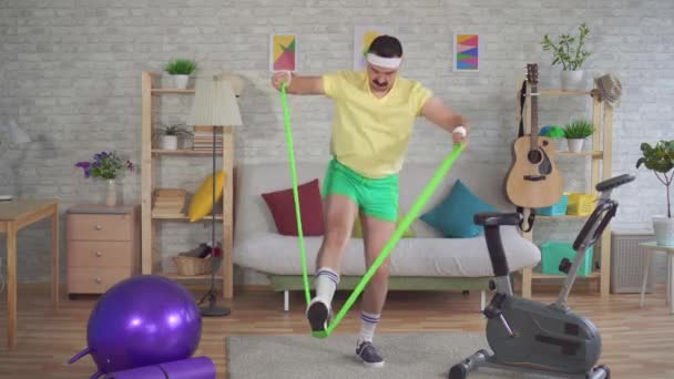 Zabawny człowiek przegrany ćwiczenia fitness w domu za pomocą gumek wchodzących — Wideo stockowe