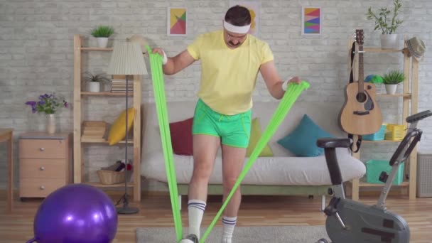 Divertente uomo perdente esercizio fitness a casa con elastici lento mo — Video Stock