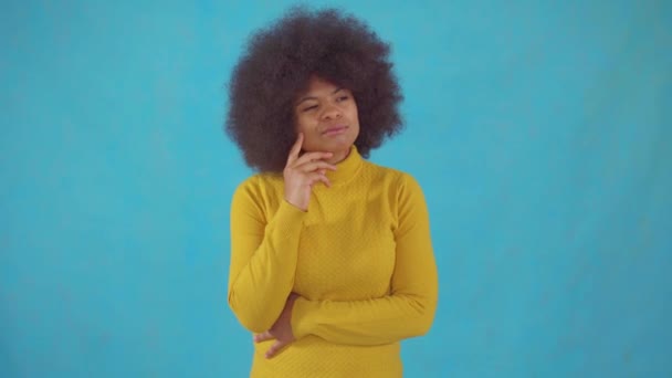 Mujer africana reflexiva con un peinado afro en una chaqueta amarilla encuentra una solución — Vídeo de stock