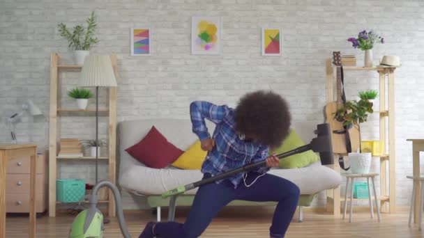 Heureuse femme africaine avec une coiffure afro joue la serpillière de l'aspirateur comme une guitare lente mo — Video