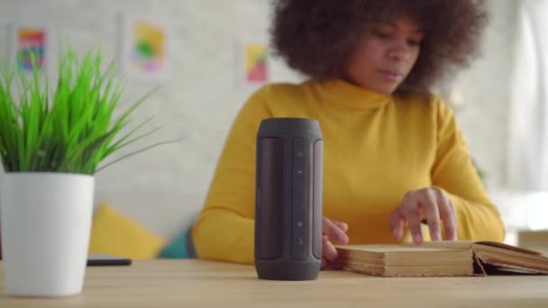 Portret Afrikaanse vrouw met een Afro kapsel geniet Voice Assistant lezen van een boek aan de tafel — Stockvideo