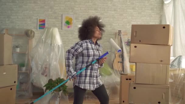 Mujer afroamericana feliz bailando y cantando con rodillo de pintura como guitarrista — Vídeos de Stock