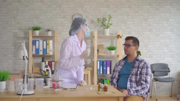 Kadın doktor alma bir tükürük test gelen bir Mans ağız ile bir pamuk çubukla — Stok video