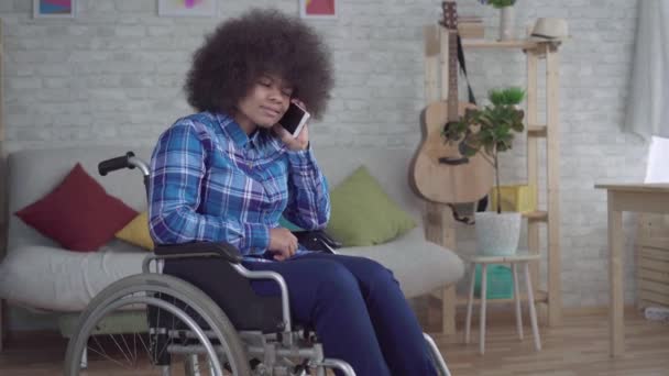 車いすの楽しみでアフロの髪型をしている障害のあるアフリカ系アメリカ人の女性電話で話す — ストック動画
